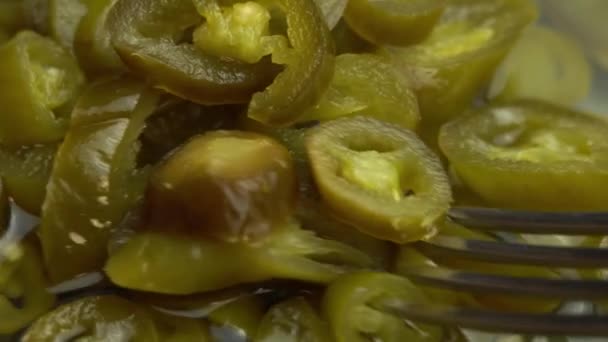 En gaffel tar skivad inlagd jalapeno paprika rotera som bakgrund, närbild är inlagd jalapeno chili paprika — Stockvideo