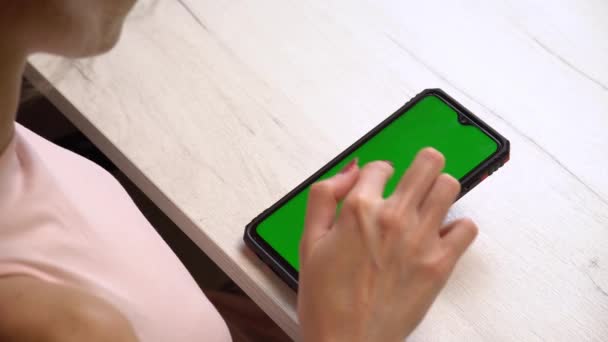 A girl during a manicure uses a smartphone with a green screen. Selfmade manicure service. Manicurist paints nails with pink gel polish. Manicured red nails. Nail polish application. — Stock Video