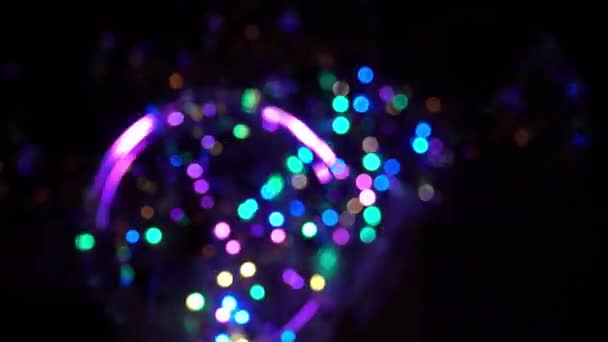 Gekleurde bloemenslinger knipperend in het donker. Abstracte feestelijke achtergrond met veelkleurige bollen geplaatst op een vlak en flitslamp neon lichten willekeurig in het donker. Neon lampen voor show of evenementen. — Stockvideo
