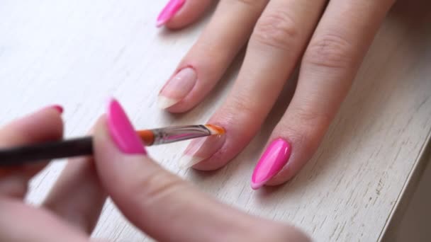 Nakładanie podkładu przed lakierowaniem paznokci lakierem do paznokci. Samodzielna usługa manicure. Manikiurzystka maluje paznokcie różowym lakierem żelowym. Różowe paznokcie. Zastosowanie lakieru do paznokci. — Wideo stockowe