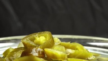 Dilimlenmiş jalapeno biberi turşusu arka planda döner, yakın planda kırmızı biber turşusu.