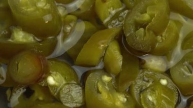 Dilimlenmiş jalapeno biberleri arka plan olarak döner, yakın plan acı biber turşusu.