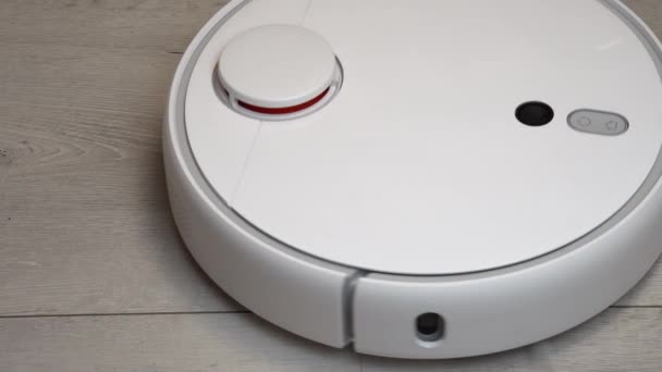 Robot vacuum cleaner in the living room. Modern vacuum Robot auto cleaning at home. Robot vacuum cleaner cleans the wooden floor — Stock Video