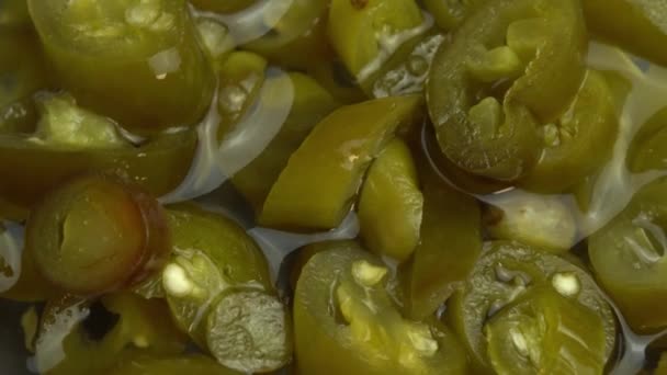 Skivad inlagd jalapeno paprika rotera som bakgrund, närbild av inlagd chili jalapeno paprika — Stockvideo