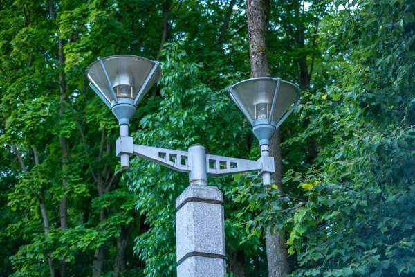 Уличная лампа в парке на фоне зеленых деревьев, современная уличная лампа, дорогой мраморный фонарь — стоковое фото