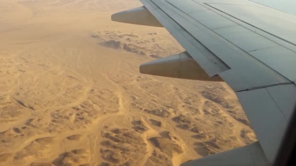 Flugzeug fliegt über die Wüste, der Blick vom Bullauge auf die Tragfläche des Flugzeugs und die Klappen. — Stockvideo