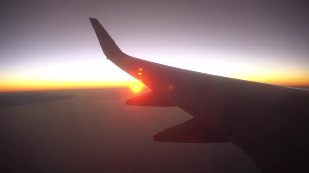 Salida del sol desde el plano de portilla, vista del ala desde la ventana del avión, plano de silueta en la salida del sol — Vídeos de Stock