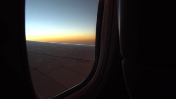 Blick aus Bullauge Flugzeug fliegt über den Himmel bei Sonnenuntergang oder Sonnenaufgang, der Blick aus dem Fenster auf den Flügel des Flugzeugs und Klappen. — Stockvideo