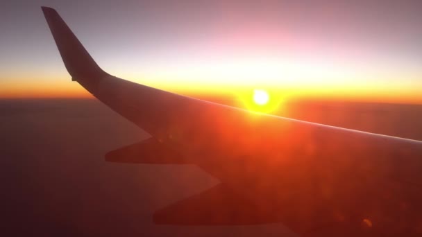 Ala de avião ao nascer do sol bloqueia a luz solar. Vista da janela do avião. Voo de avião ao pôr-do-sol. Viajar por via aérea. — Vídeo de Stock