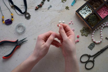 Mücevherleri yapıyorum. Bilezik yapmak için dikiş aksesuarları, boncuklardan zincir. DIY projesi. Küçük bir iş. Hobiden gelir..