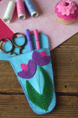 Pembe ve mor çiçeklerle süslenmiş makaslar için dava açmak. Keçeden kendi ellerinle dikmek. Çocuklar için DIY konsepti. El yapımı el sanatları.