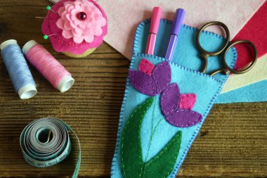 Pembe ve mor çiçeklerle süslenmiş makaslar için dava açmak. Keçeden kendi ellerinle dikmek. Çocuklar için DIY konsepti. El yapımı el sanatları.