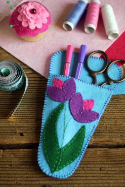 Pembe ve mor çiçeklerle süslenmiş makaslar için dava açmak. Keçeden kendi ellerinle dikmek. Çocuklar için DIY konsepti. El yapımı el sanatları.