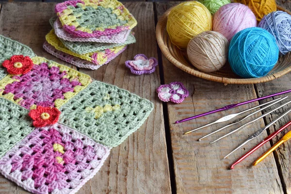 Equipment for knitting and crochet hook, olorful rainbow cotton yarn, ball of threads, wool, knitted elements, napkin . Granny square. Handmade crocheting crafts. DIY concept. Copy space.