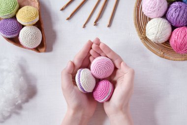 Making crochet amigurumi french macarons. Toy for babies or trinket.  Threads, needles, hook, cotton yarn. Handmade gift. Income from hobby. DIY crafts concept.