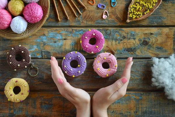 Making crochet amigurumi donuts. Toy for babies or trinket.  On the table threads, needles, hook, cotton yarn. Handmade gift. Income from hobby. DIY crafts concept.