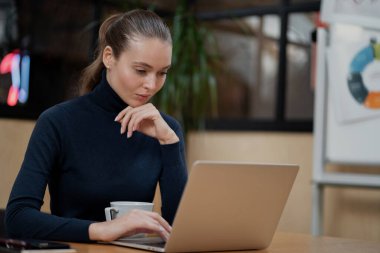 Güzel genç bayan ofiste yalnız oturuyor. Çalışıyor.