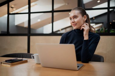 Gri bir dizüstü bilgisayar üzerinde çalışıyor. Yeni bir statü düşünüyor.