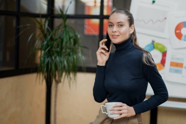 Elinde sıcak aromatik bir fincan kahve tutuyordu. Orada oturuyor.