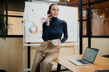 Güzel, genç bir kadın elinde bir telefon tutuyor.