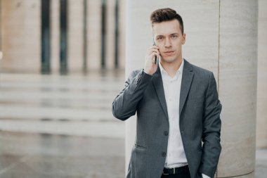 Elinde yeni bir telefon tutan zeki erkek öğrenci bir arkadaşına bir mesaj yazar.