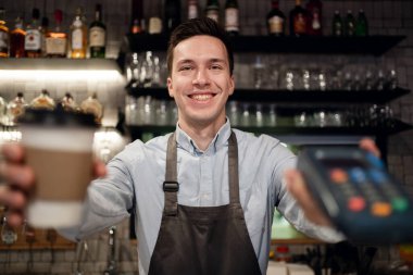 Küçük bir restoranda çalışan bir eleman önlük ve gömlekle çalışır.