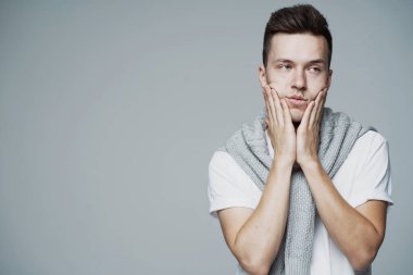 Yorgun eller, beyaz görünümlü genç bir adamın yüzünü sıkar.