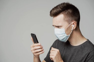 Kafkas görünümlü bir adam telefona bakıyor, maske takıyor.