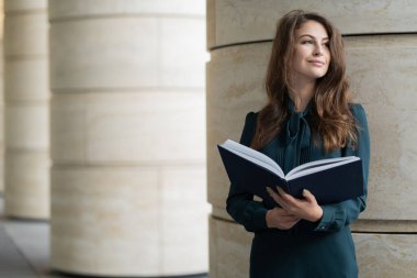 Güzel bir öğrenci, elinde bir dizüstü bilgisayarla W dosyasını tutuyor.