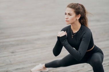 Genç bir atlet bacak esnetme egzersizi yapıyor. Siyah bir spor.