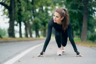 Atletik yapılı kendine güvenen bir kadın, ayakta duruyor. 
