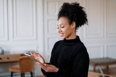 Bir bayan öğrenci internette çalışırken gülümsüyor.