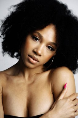 Kulağında küpeler var. Siyah, sağlıklı kıvırcık saçlar. Profesyonel mak