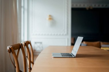 Açık bir dizüstü bilgisayar şık bir ofiste masanın üzerinde durur. Çalışan mola vermek için gitti.