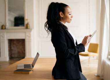 Video bağlantısı ile çevrimiçi uzaklık öğrenme. Muhasebeci tabletteki çevrimiçi tablodaki krediyi hesaplar. Müşteriye bir e- posta iletisi yazdırır. Ofiste çalışan bayan yönetici gülümsüyor..