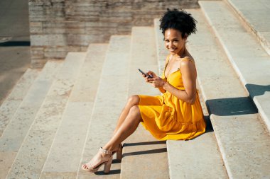 Mola sırasında dizüstü bilgisayara bir mesaj yazar. Telefonunda internette geziniyor. Brezilyalı genç bir kadın bir yaz parkında online antrenman yapıyor..