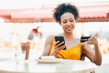 İnternetten kredi kartıyla online sipariş veriyor. Elinde bir cep telefonu kullanıyor. Brezilyalı genç bir kadın bir yaz parkında online antrenman yapıyor..