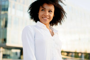 Zeki bir öğrenci üniversitenin yanında duruyor, kıvırcık saçlı ve beyaz, rahat gömlekli. Yüzünü çeviren Afro görünümlü bir menajerin portresi. Harika bir gelecek düşünüyor..