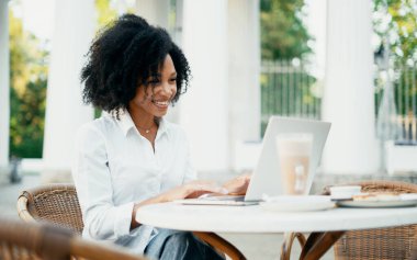 Yazlık bir kafede çalışıyor. Bir öğrenci aboneliklerine bir sosyal ağ üzerinden dizüstü bilgisayara mesaj basıyor. Bilgisayarda çalışan, gülümseyen Afrikalı Amerikalı bir yönetici..