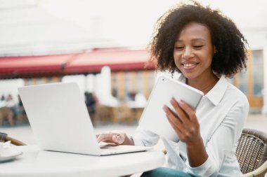 Müşteriye e-posta ile bir mesaj yazar. Sokakta dizüstü bilgisayarla çalışan bir öğrenci. Blogcu kıvırcık saçlı, Afro-Amerikan görünümlü genç kadın şehirdeki bir iş merkezinin yakınında..