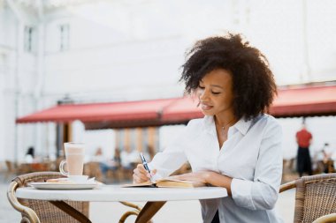 Bir Afro-Amerikalı serbest çalışıyor. Proje planlarını bir günlüğe yazıyor. Beyaz gömlekli bir bayan müdür şehirde bir yazlık kafede oturuyor..