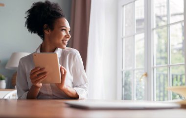 Blogcu bir tablet üzerinde çalışıyor. Öğrenci bir cihaz kullanıyor. Serbest portre çalışanı müşterilerine evdeki sosyal ağda bir mesaj basar. İnternette sörf yapan bir kadın.