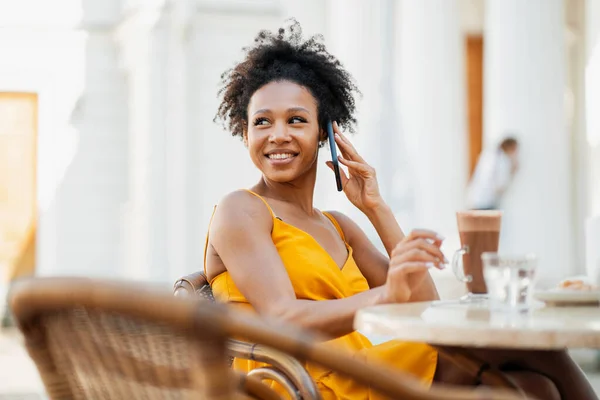 一个女人对着一个与朋友通电话的非洲裔学生笑了 自由职业者用的是小工具 — 图库照片