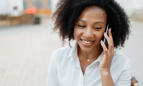 通过信使电话给客户打电话 一个穿着白色非洲衬衫的聪明的学生面带微笑 一位自信的女经理在办公室附近工作 — 图库照片