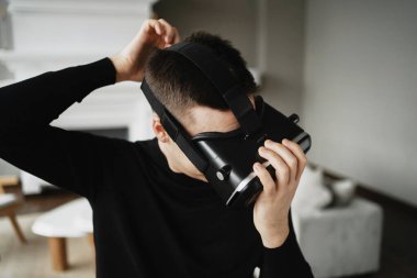 Kafasına siyah bir kask geçirir. Bir VR programcısı 