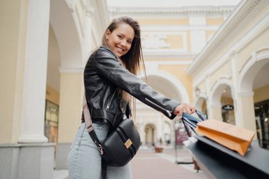 Elinde kıyafetlerle bir kaç farklı boyutta çanta tutuyor..