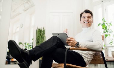 Müzik okulunda bir erkek öğretmen. Sandalyeye oturup ders planı olan bir tableti tutmak. Yetişkin yaratıcı bir insan..