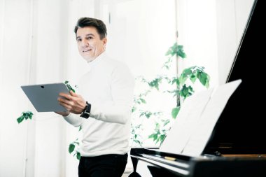 Uygulamandaki müzik notaları. Erkek sanatçı, müzik okulunda 50-60 yaşlarında bir öğretmen. Evde piyano çalıyor. Dairede. Güzel klasik müzik..