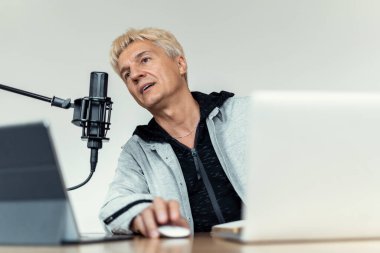 Bir gazeteci ve bir laptop. Radyo sunucusu iyi haberler gönderiyor. Mikrofona konuşuyor. Podcast programının canlı yayın kaydı. Radyodaki bir blog yazarı dinleyicilerle iletişim kuruyor..