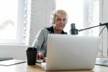 İnsanlarla mikrofon aracılığıyla iletişim kuruyor. Radyo sunucusu erkek bir kayıt stüdyosunda çalışıyor..